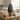 Artificial cypress tree in a rustic terracotta pot on a wooden side table, styled with books and a candle in a neutral living space