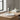 Diffuser with sticks on a white round base on a wooden surface.