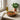 Rounded wooden serving bowl on table, in front of plant and with wooden fork and spoon.