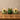 Three lit candles in glass containers on a wooden surface with a neutral background