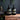 Two dark bottles with pump dispensers on a wooden surface, with a dark wall and sink in the background.