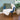 Blue chair with a cream faux fur blanket and green pillow in a room with a plant.