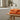 Orange towels on a wooden bench in a bathroom setting with a bathtub and decorative items.