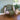 Pink armchair with a green cushion and blanket next to a potted plant on a wooden floor.