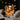 Decorative LED candle with pumpkin design against a dark background with string lights.