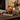 Candle with pumpkin design on a wooden surface with blurred lights in the background