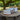 Three rustic metal buckets on a garden table with trees and greenery in the background