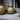 Two gold textured vases on a concrete surface with a neutral background. 