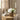 White roses in a woven basket on a wooden side table with candle