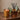 A lit amber glass candle gift set and a matching amber reed diffuser bottle with black reeds and a gold cap