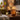 An amber glass candle holder with warm fairy lights and autumn-themed illustrations on a wooden table
