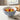 Bowl of salad with cherry tomatoes on a table with bread and a napkin.