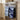 Two navy blue printed tea towels hanging from a stainless steel oven handle in a beige kitchen.