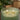 Two lit candles in a textured glass container on a wooden surface with a blurred background