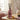 Pink diffuser bottle with black sticks on a table with decorative elements