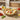Round dip dish containing nachos, surrounded by tomatoes on a tabletop.