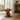 A fluffy, cute highland cow doorstop sits on a woven jute runner in front of an open white door on a wooden floor