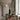 A diffuser bottle on a wooden surface with a decorative vase and plant in the background.