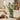 A fake indoor olive tree in a decorative tin pot, styled on a wooden countertop