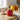 Red glass jar on kitchen countertop next to teacup, with a yellow jar and an orange one in background.