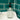 Clear glass soap dispenser with black pump on a sink against teal tiled wall