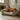 Red Labrador lying on a patterned green dog bed in a room with cabinets and boots.