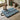 Floral-patterned dog mat on a stone floor with a spaniel dog sitting on it, next to green wellies and a basket.