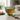 Green glass mug with textured design filled with tea on a wooden table.