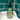 Green soap dispenser with black pump on a white sink against teal tiled wall