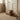 A fluffy brown Highland cow door draught excluder sits on a stone floor in a softly styled room