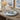 A light blue decorative round tray styled on a stone console table, holding a diffuser and candle