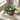 Green ceramic candle holder with a lit candle on a wooden surface.