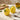 Two ceramic lemon-shaped salt and pepper shakers on a table with a plate and oil bottle in the background.