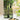 Two green glass bottles labeled 'Oil' and 'Vinegar' on a black metal stand with a window and plants in the background.