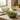 Three green glass bowls on a kitchen counter with olives and a bottle of olive oil.