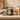 A lit Candlelight luxury scented candle in an olive green glass jar on a stone surface