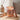 A lit glass cassis candle jar with a lid leaning beside it on a round wooden table.