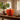 An orange paper piece of pumpkin décor styled on a rustic wooden table next to a ceramic vase