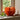 An orange piece of paper pumpkin décor displayed on a windowsill next to an oak leaf sprig