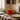 An orange piece of paper pumpkin décor sits on a rustic wooden dining table set with white plates
