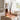 A scented reed diffuser set styled on a light wood tray in a bright bedroom or living space.