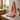A folded set of designer tea towels with a dark red architectural pattern displayed on a marble countertop