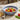 Bowl with cherry tomatoes and basil leaves on a textured surface with bread and a glass.