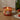 Lit scented candle on wooden countertop, next to tomatoes with a wine bottle and a white tea towel.