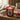 A lit red glass fragrance candle jar labeled 'Scottish Raspberry' by Candlelight, on a wooden table