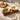 Wooden bowls on tray containing cream snacks, on white countertop.