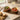 Pair of wooden bowls containing olive and tomato snacks on tray.