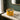Candle in a glass jar with decorative design on a marble surface near a window.