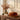 An orange velour pumpkin cushion on a tabletop, surrounded by books, leaves and a candle