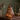 An amber glass pumpkin table lamp with a stem, filled with warm fairy lights, sitting on a wooden table